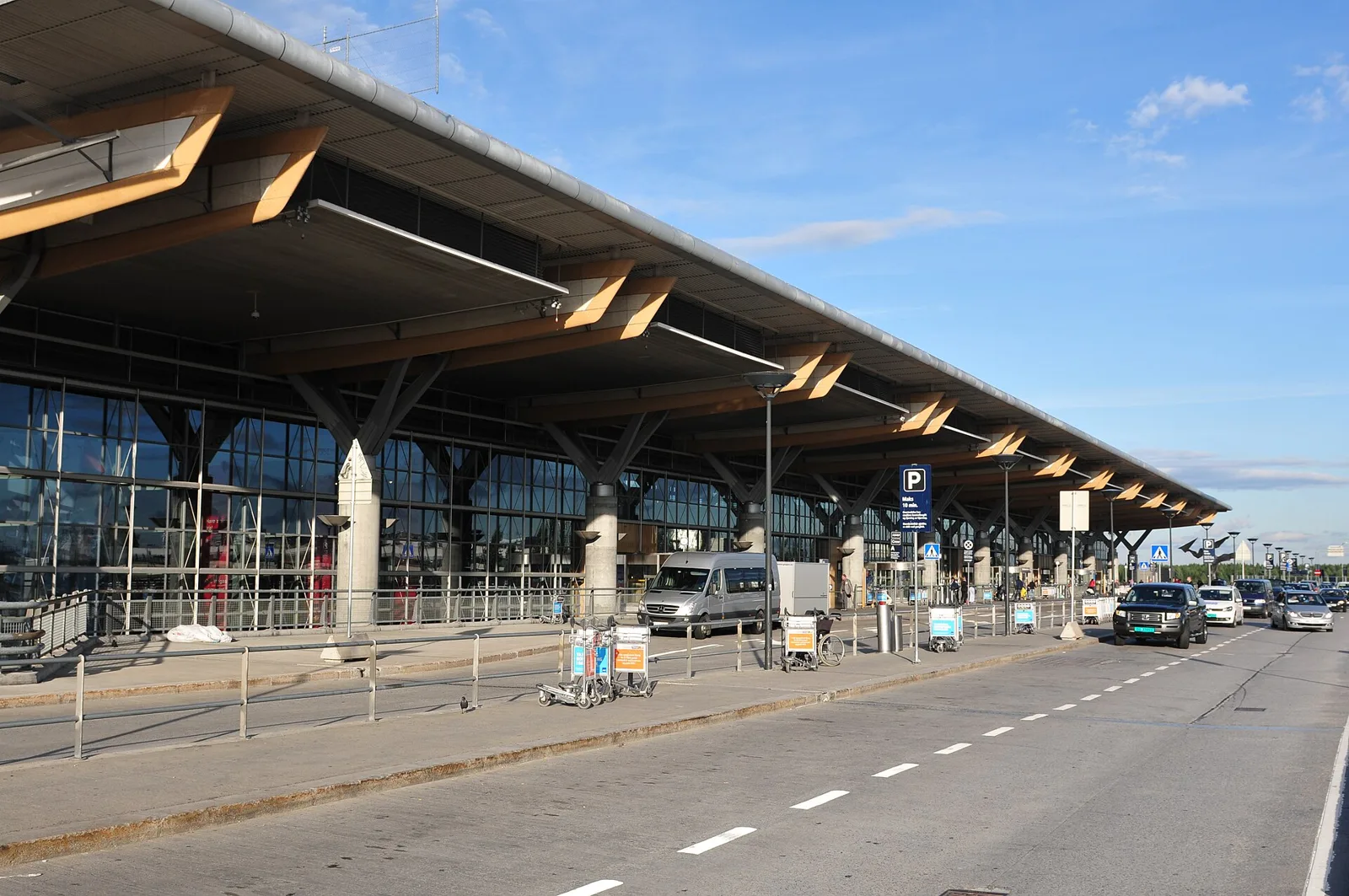 Façade du terminal de l'aéroport d'Oslo-Gardermoen, avec sa toiture en bois et ses piliers, côté arrivées