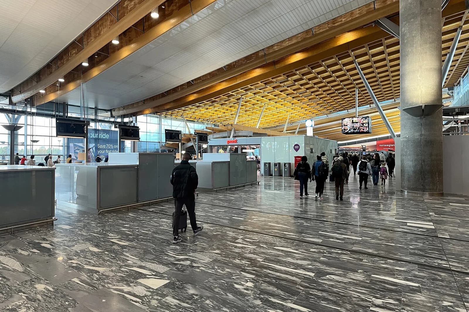 Hall du terminal de l’aéroport d’Oslo-Gardermoen, avec sa charpente en bois et son sol en pierre