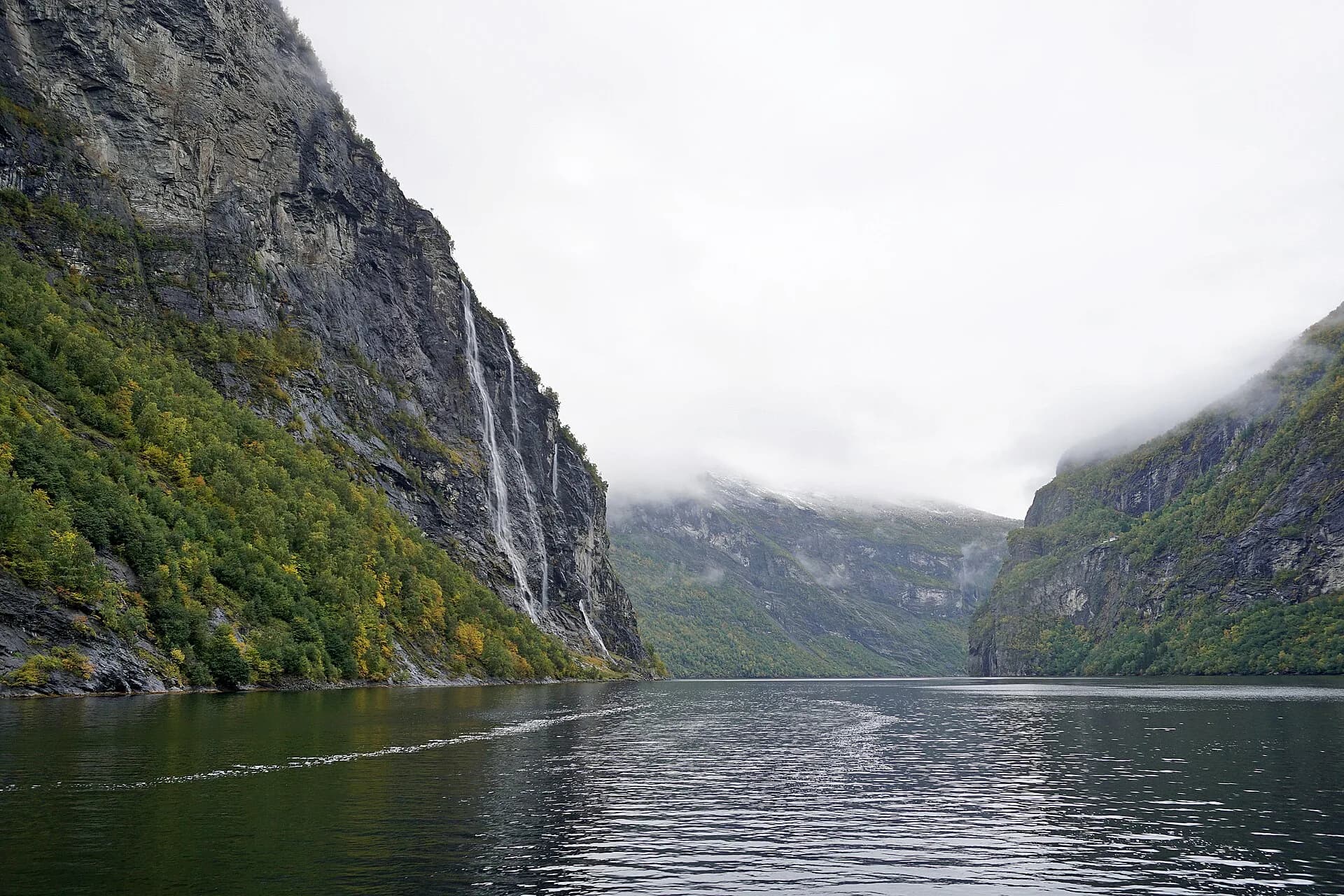 Les cascades des Sept Sœurs tombant d’une paroi du Geirangerfjord, vues depuis un bateau, par temps brumeux