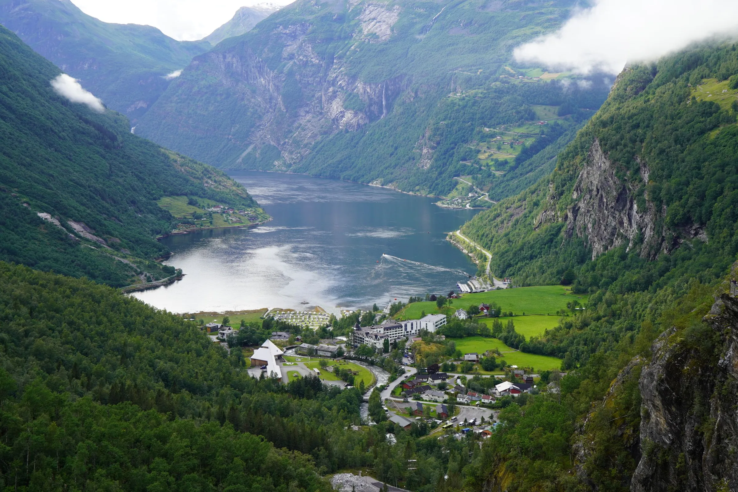 Vue aérienne du village de Geiranger au fond du Geirangerfjord, entouré de falaises verdoyantes