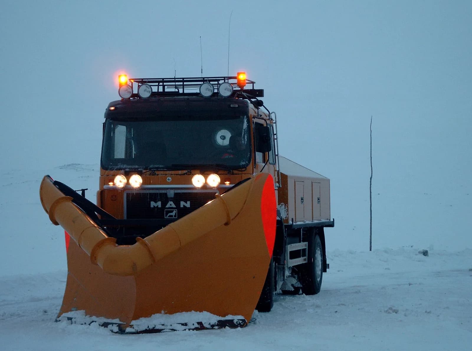 Chasse-neige en tête d’un convoi, entre les piquets de neige, à Haugastøl sur la Rv7 (Hardangervidda)