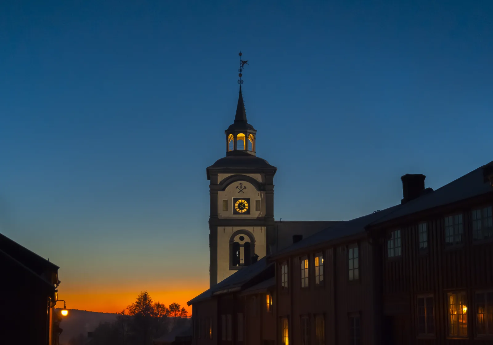 L’église de Røros vue depuis Kjerkgata, à la tombée de la nuit d’hiver, maisons en bois éclairées
