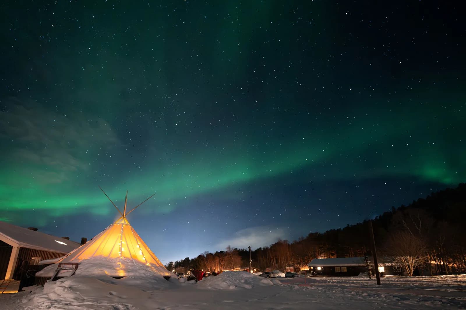 Lavvu éclairé sous les aurores boréales dans la neige près d’Alta, dans le Finnmark