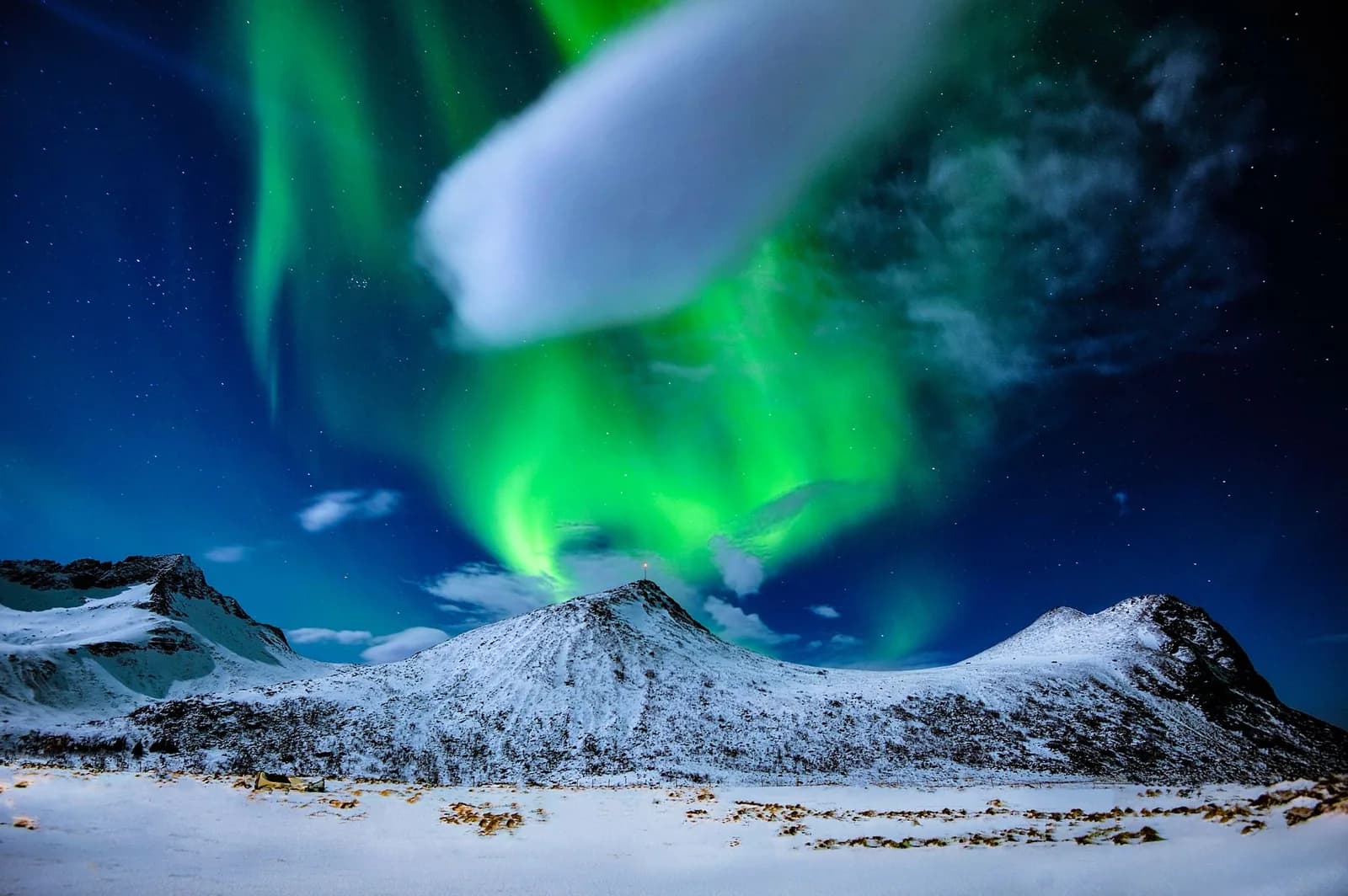 Aurore boréale verte au-dessus de montagnes enneigées dans le nord de la Norvège