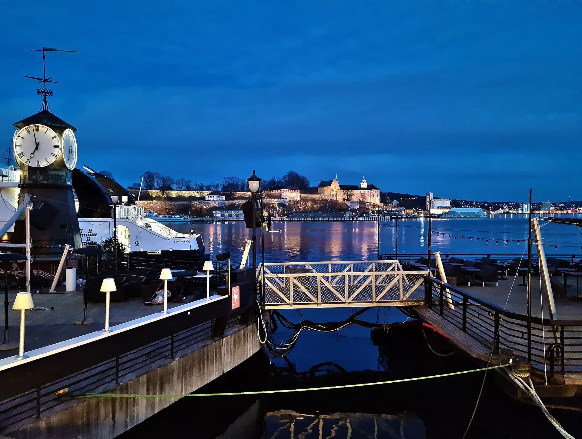 Le quai d'Aker Brygge à la tombée de la nuit, avec la forteresse d'Akershus en fond